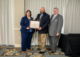 Joshua Mann (center), DESC's Chief of Operations for Radio Communications Maintenance, receives his certificate after completing rigorous coursework to become a Certified Public-Safety Executive.